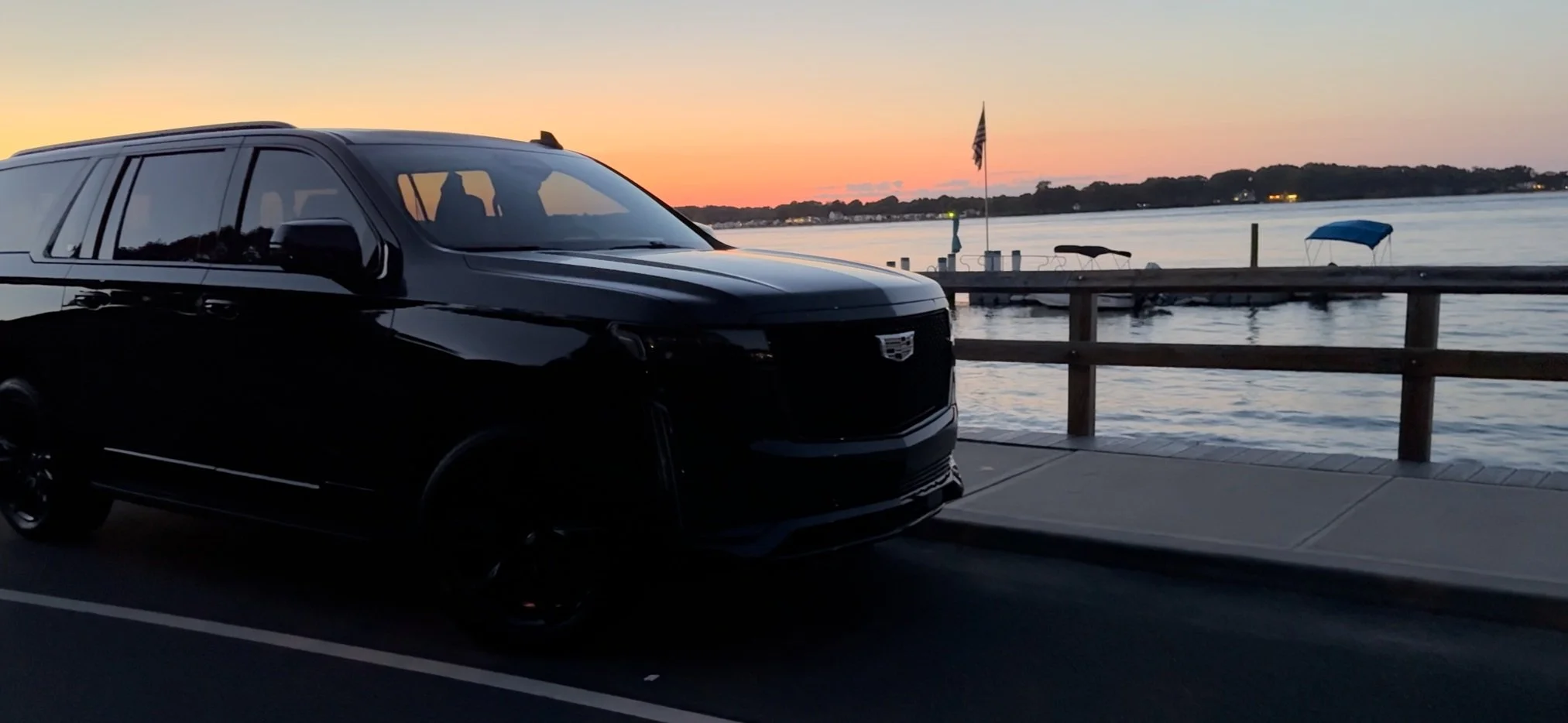 Black Cadillac SUV with the New York City skyline at night