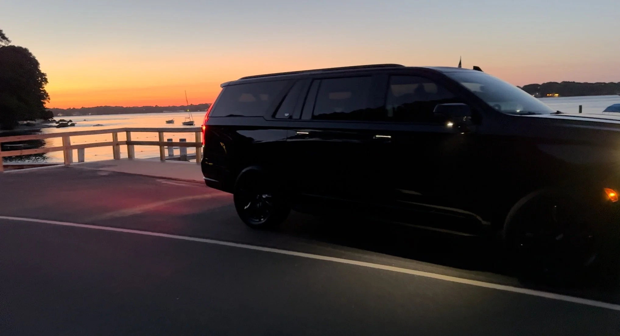 Black Cadillac Escalade beside the water at sunset